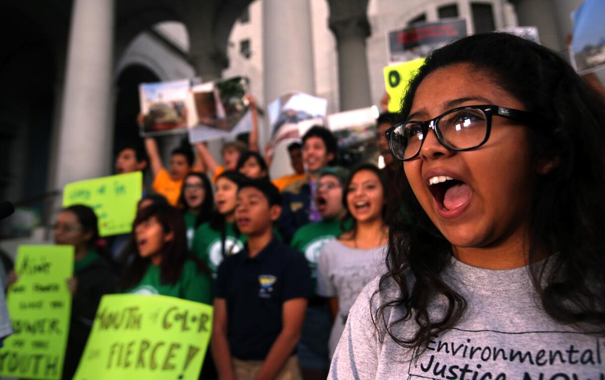 Isis Reyes, 16, right, who lives in Wilmington, joins other young plaintiffs at L.A. City Hall after a new lawsuit was filed agianst oil drilling operations close to homes and school.