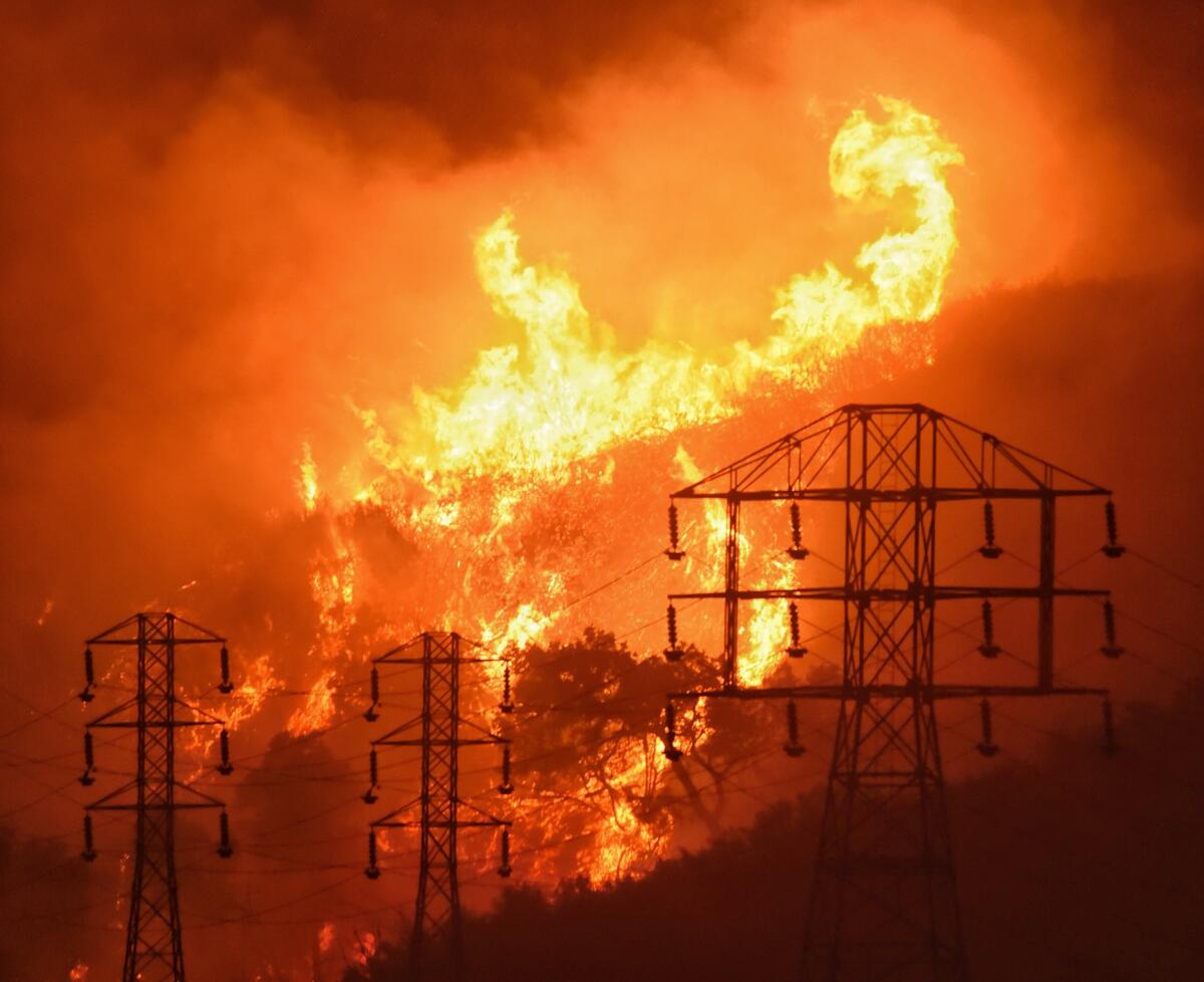 A wildfire burns behind power lines