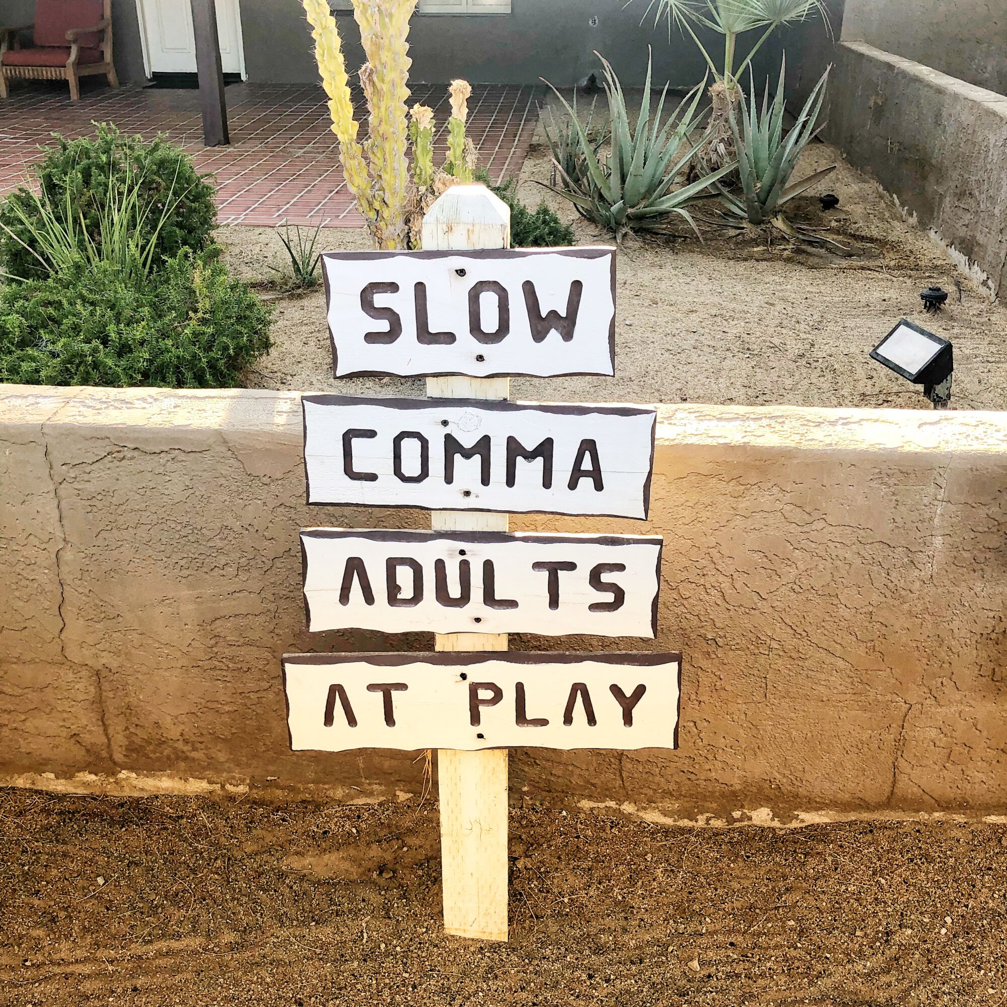 A sign reading "Slow comma adults at play"
