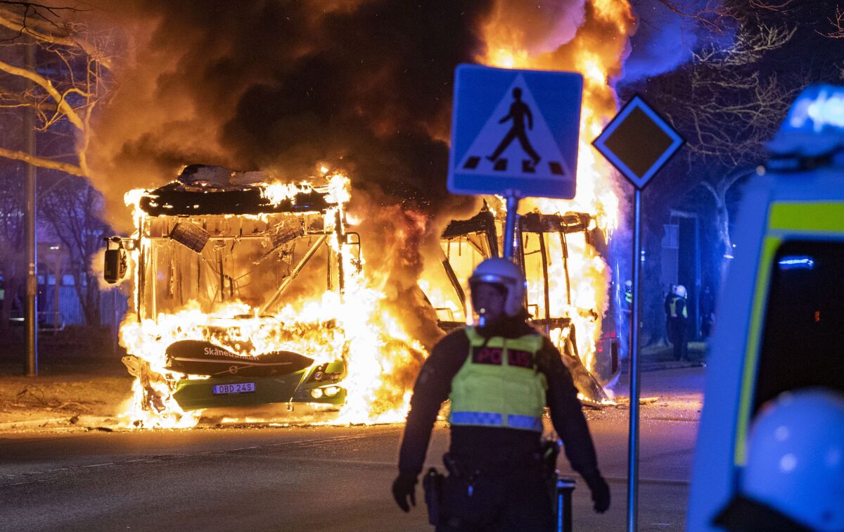 Riot police watch a city bus burn on a street in Malmo, Sweden, Saturday, April 16, 2022. Unrest broke out in southern Sweden late Saturday despite police moving a rally by an anti-Islam far-right group, which was planning to burn a Quran among other things, to a new location as a preventive measure. (Johan Nilsson/TT via AP)