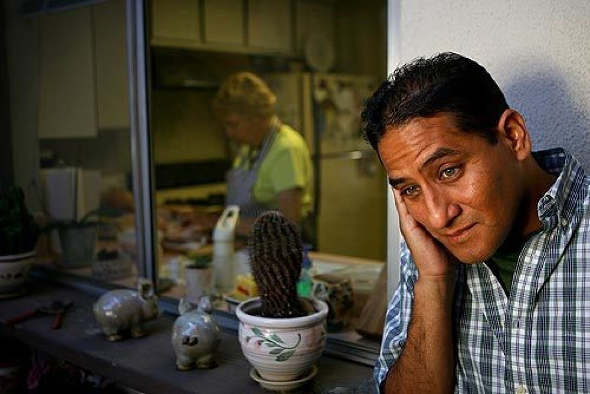 Luis Garcia, a successful physician from Peru, still needs to pass the U.S. licensing exams. While studying, he takes care of cats, dogs and elderly people in Southern California. Garcia is shown at the residence of Dusha Cvjetkovic (in the background cooking), whose home and cat he's cared for intermittently over the last two years. Cvjetkovic, originally from Croatia, says that although she has paid Garcia to help her with her garden, her cat and her home, she would be embarrassed to ask him to do dirtier jobs. "In my country a doctor is someone to be very respected," she said.
