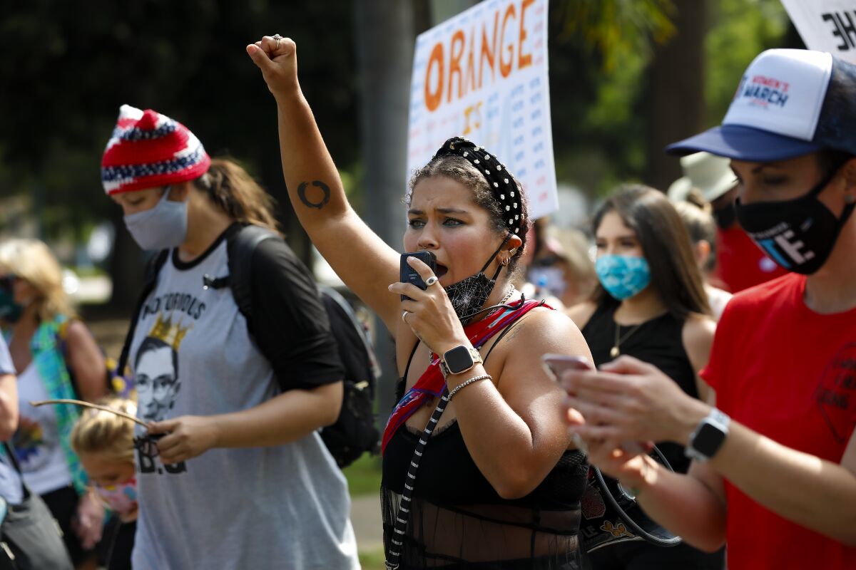 Athena Bazalaki leads a chant on a megaphone during a women's march through Balboa Park