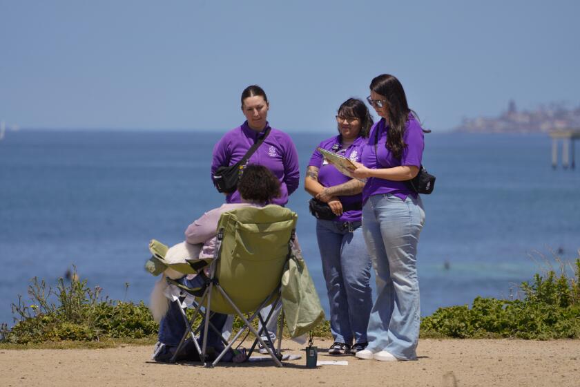 San Diego, CA - April 19: On Friday, April 19, 2024 in San Diego, CA, a MCRT team from Telecare is sent into the field to meet a caller and assess her situation. Heather Kriletich (), Dulce Hernandez (m) and Cynaera Lewis speak with the woman near the cliff’s edge. (Nelvin C. Cepeda / The San Diego Union-Tribune)
