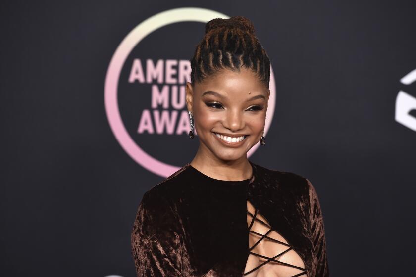 A woman with brown hair pulled back into a bun smiling in a brown velvet dress