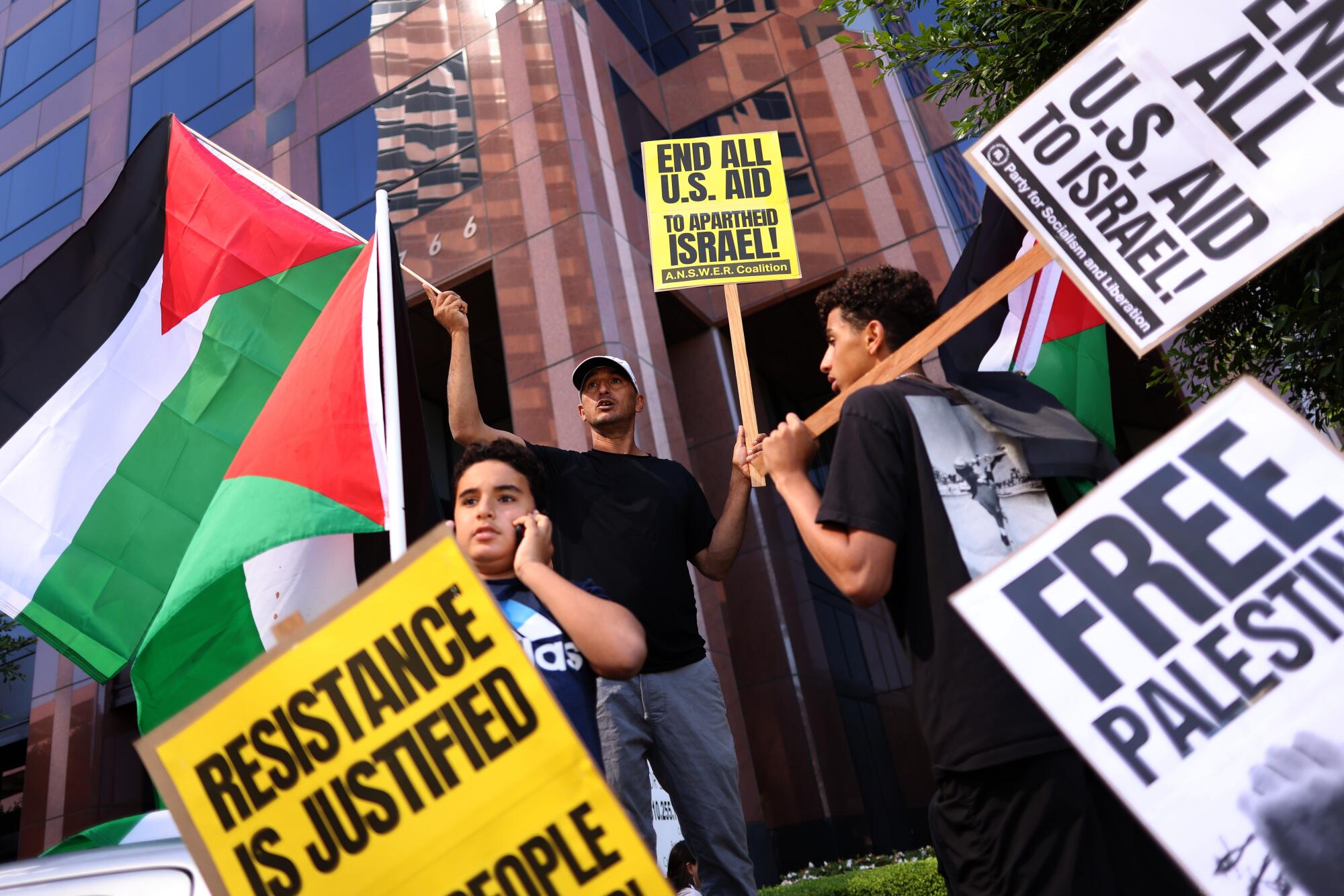 People holding signs and waving flags gather in Westwood in support of Palestinians caught in the Israel-Hamas war.