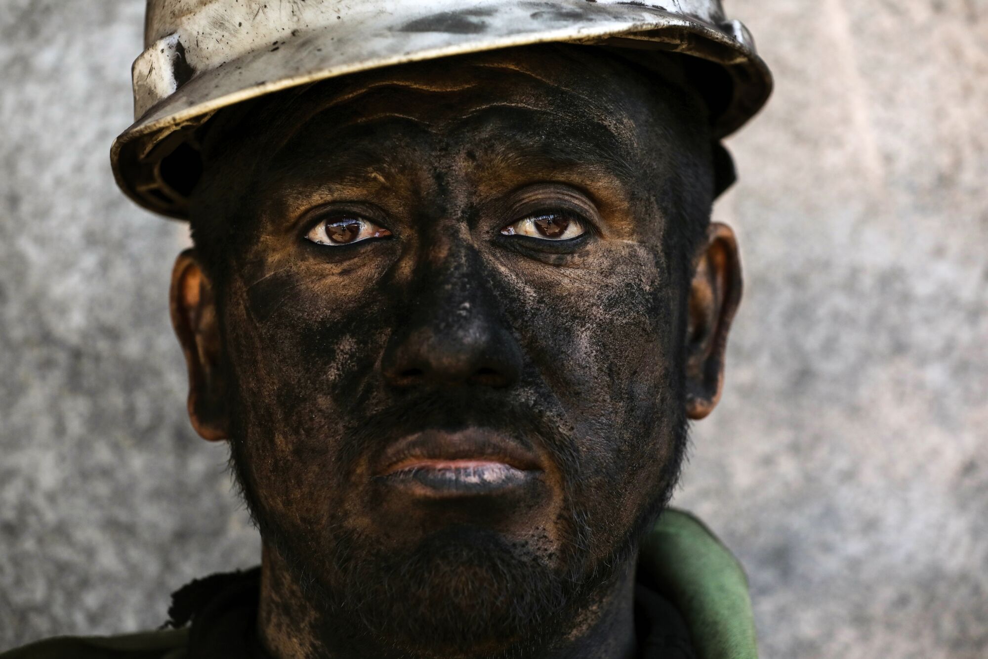 A man's face covered in black coal dust and dirt 