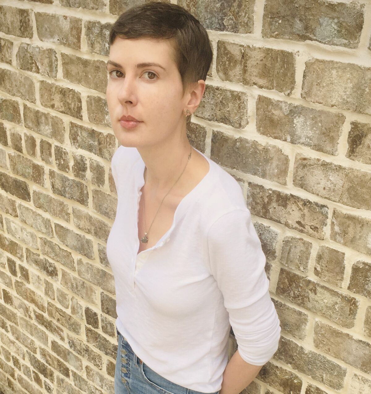 Author Patricia Lockwood stands against a brick wall.