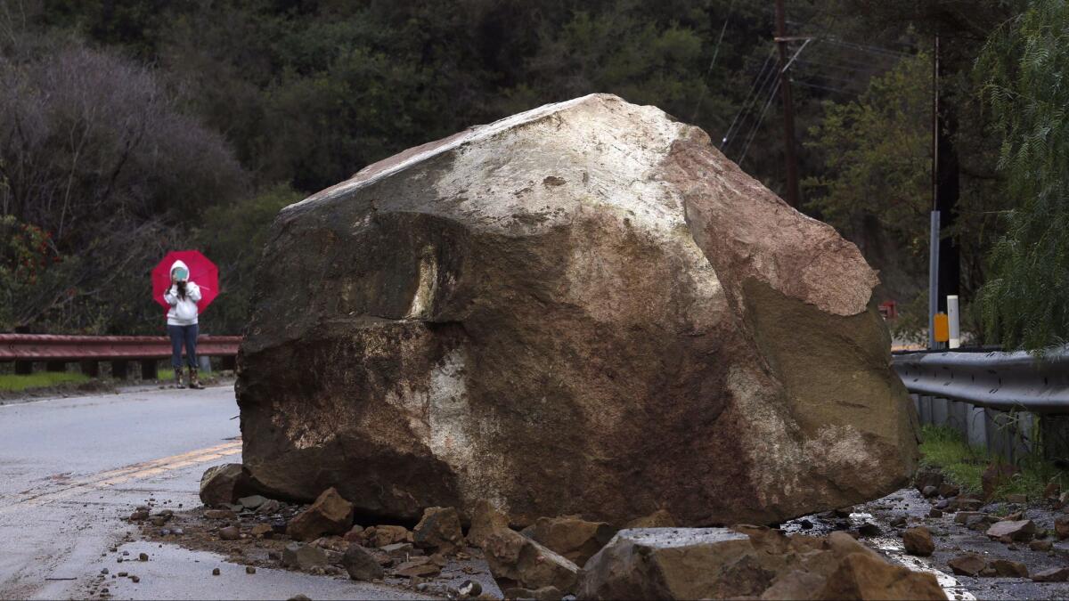 Gina Picciolo takes a picture of a boulder that fell onto Topanga Canyon Boulevard near Grandview Drive in the Fernwood area on Jan. 23, 2017. Picciolo is a longtime resident in the area. (Genaro Molina / Los Angeles Times)