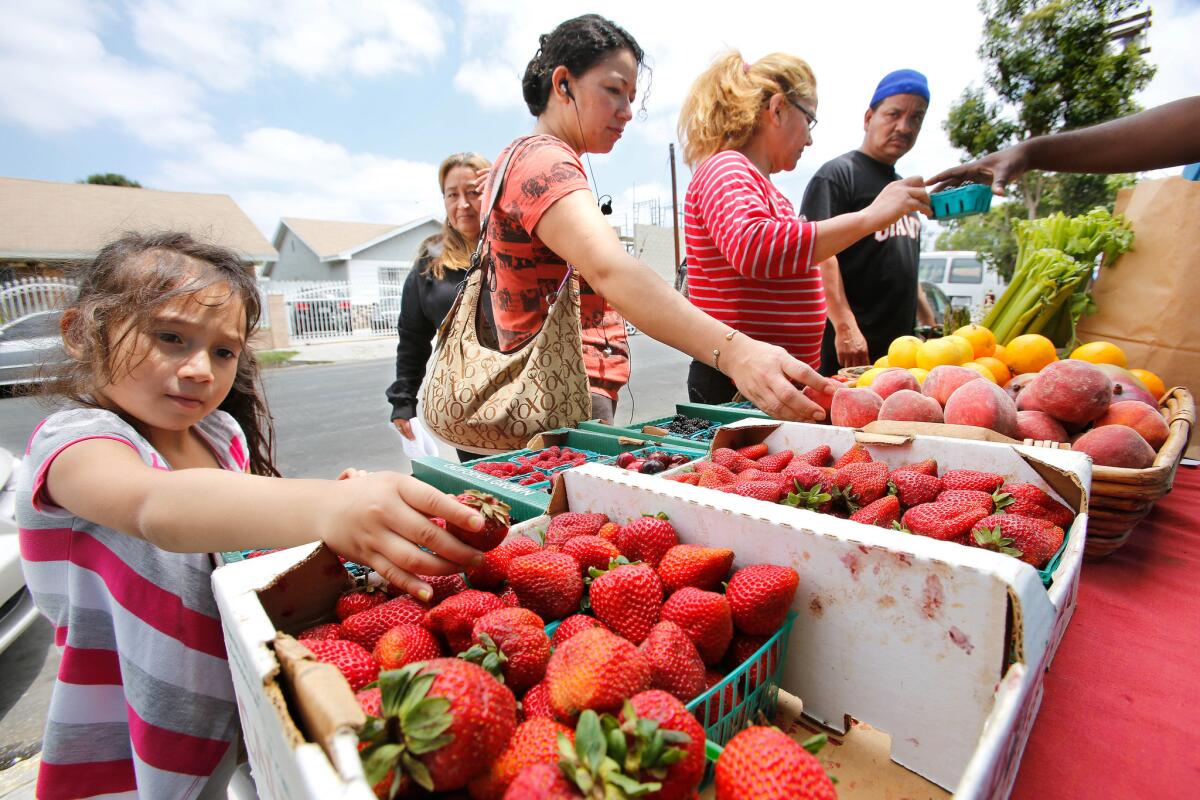 Shoppers look at fruit on display at a produce stand set up outside St. John's Well Child and Family Center's S. Mark Taper Foundation Health Center in South Los Angeles in June 2013.