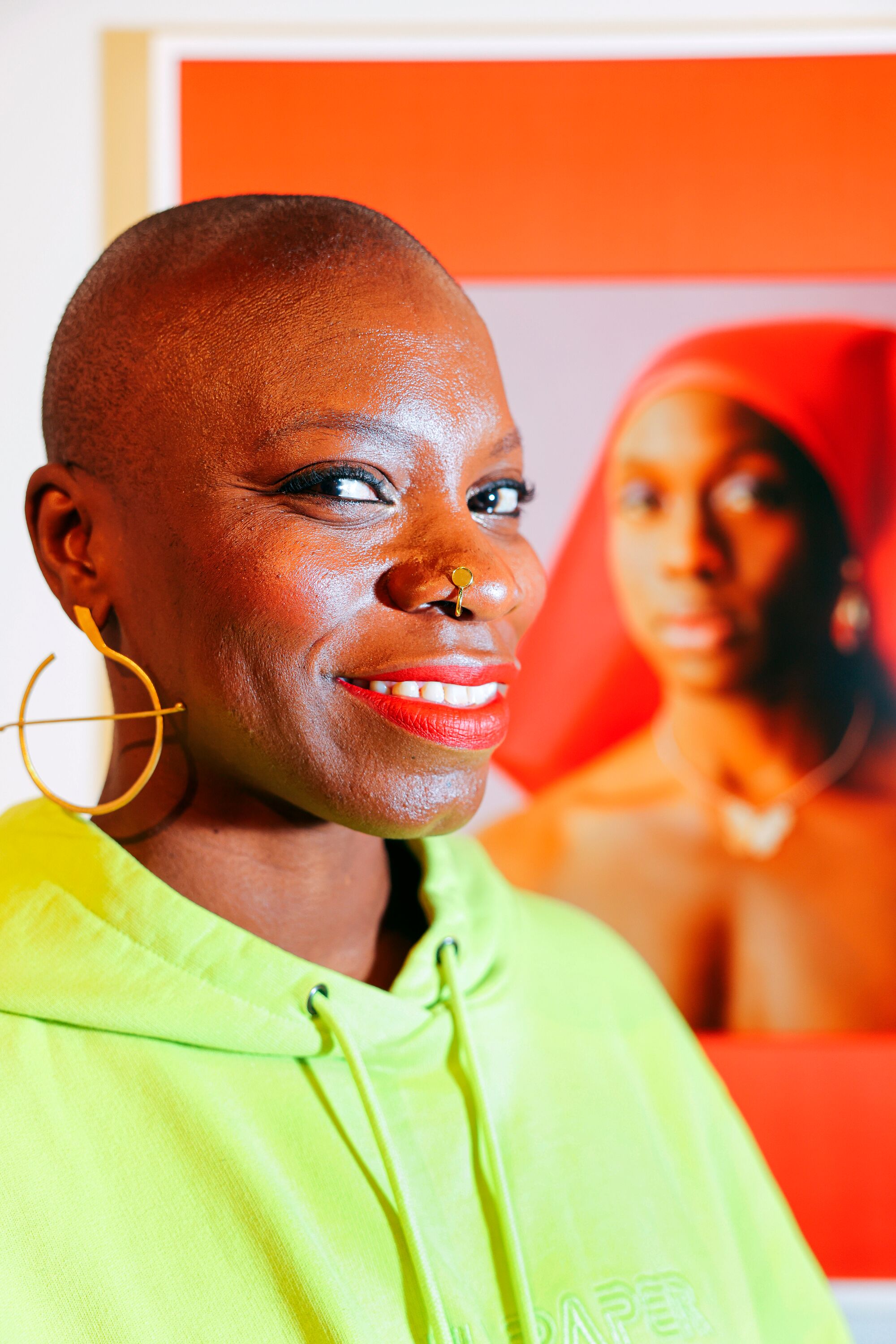 A woman in a yellow hoodie and hoop earrings poses for a photo.