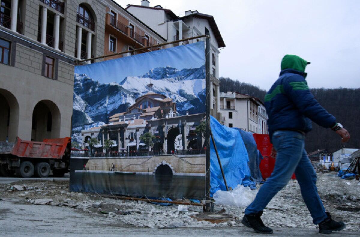 A construction worker passes a decorative fence next to a hotel in Krasnaya Polyana, Russia, in the mountains above Sochi.