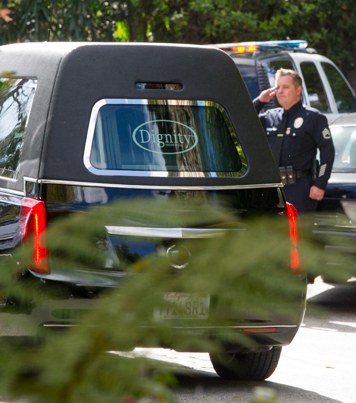 A police officer salutes as a hearse leaves the Malibu home of Nancy Reagan.