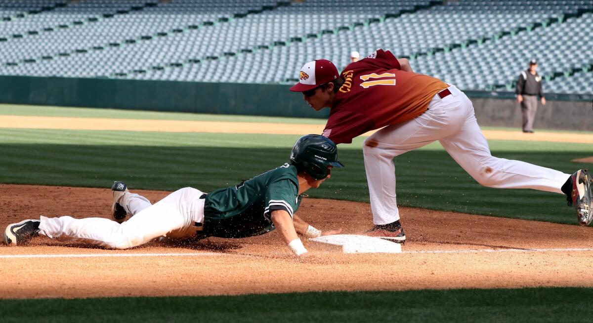 Costa Mesa's Miguel Rodriguez dives in safely into third base to avoid Estancia's Jake Covey tag in a showcase game at Angel Stadium on March 20.