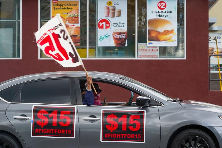 Fast-food workers drive though a McDonald's restaurant with signs protesting for a higher minimum wage.