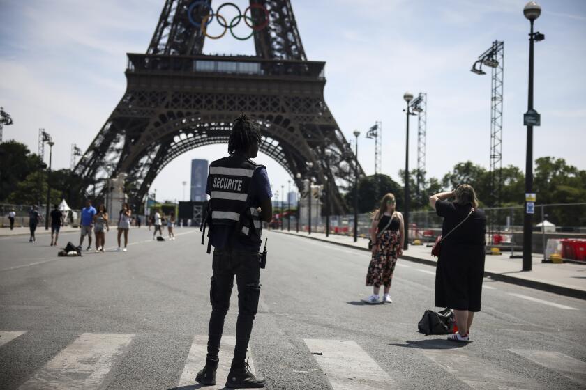 ARCHIVO - Foto del sábado 20 de julio del 2024, un oficial de seguridad observa a personas tomándose fotos frente a la Torre Eiffel antes de los Juegos Olímpicos. (AP Foto/Thomas Padilla, Archivo)