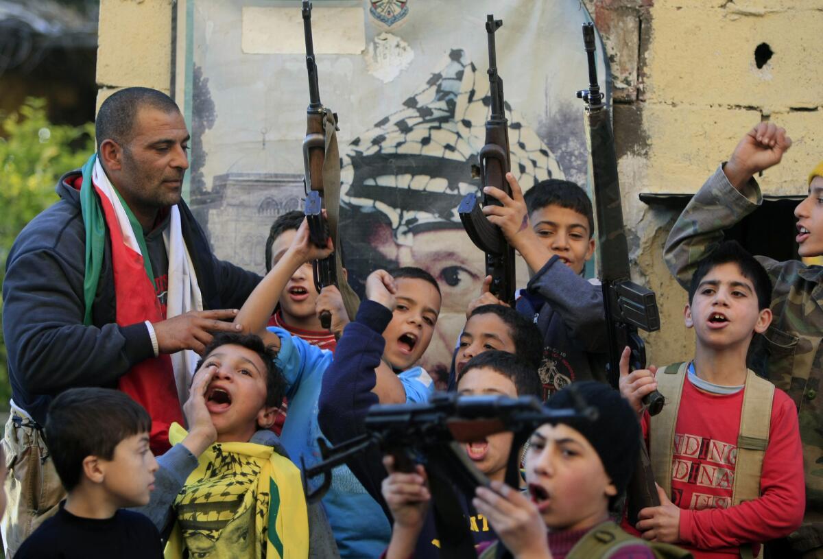 Palestinian children in the Ein el-Hilweh camp near Sidon in southern Lebanon hold up weapons and chant slogans against Israel after hearing of the death of Ariel Sharon.