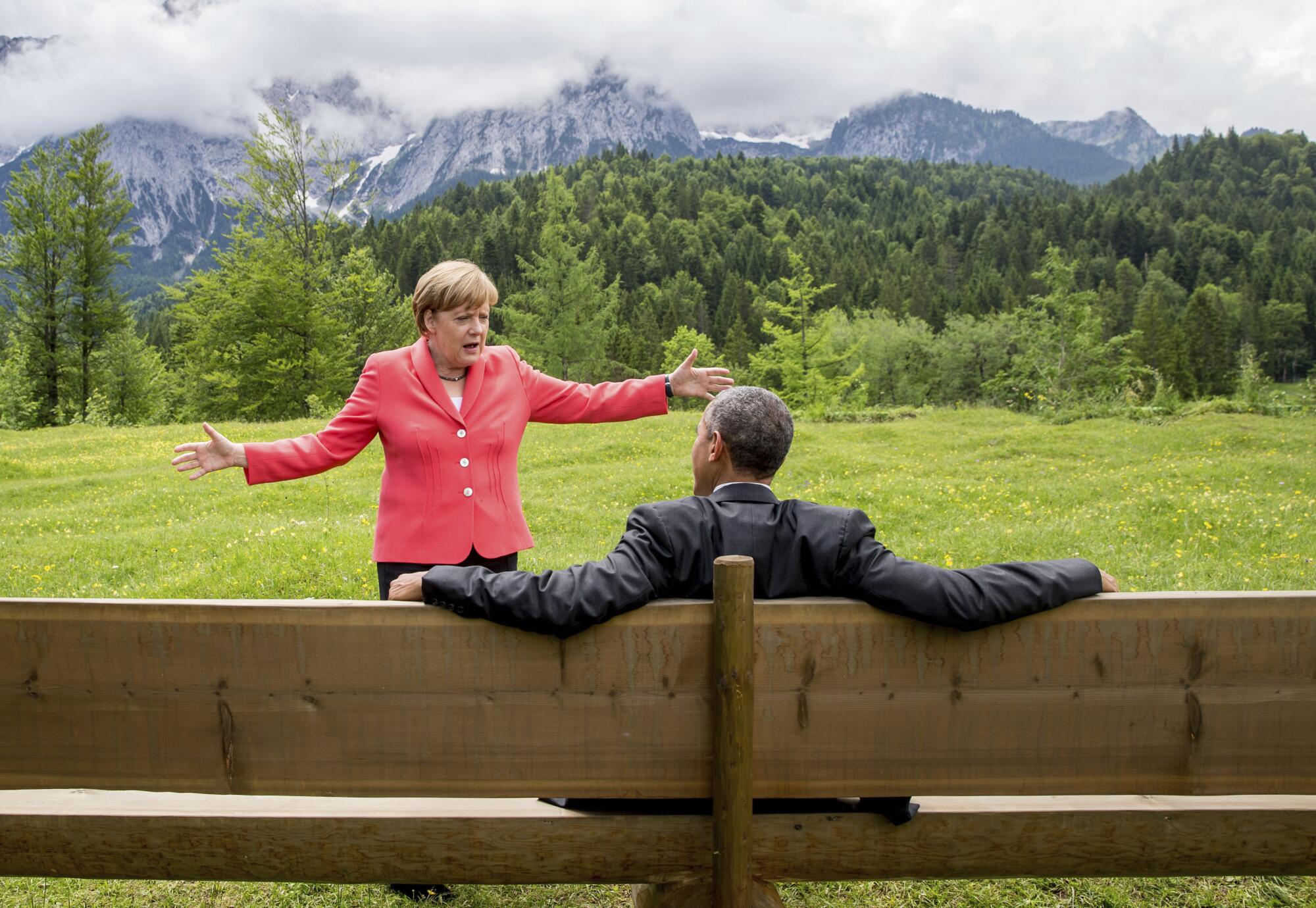 Angela Merkel talks to then-President Obama in 2015 in Germany, with a view of trees and mountains 