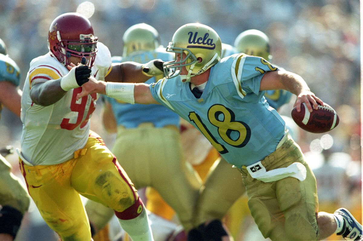 UCLA quarterback Cade McNown is being chased by USC defensive tackle Darrell Russell.