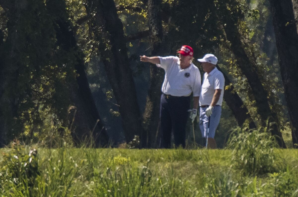 President Donald Trump and Sen. Lindsey Graham, R-S.C., right, play golf at Trump National Golf Club in Sterling, Va., as seen from the other side of the Potomac River in Darnestown, Md., Saturday, July 18, 2020. (AP Photo/Manuel Balce Ceneta)