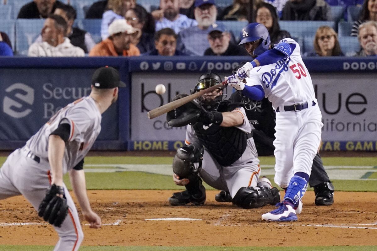 Los Angeles Dodgers right fielder Mookie Betts, right, hits a solo home run as San Francisco Giants starting pitcher Alex Wood, left, and catcher Joey Bart watch during the sixth inning of a baseball game Wednesday, May 4, 2022, in Los Angeles. (AP Photo/Mark J. Terrill)