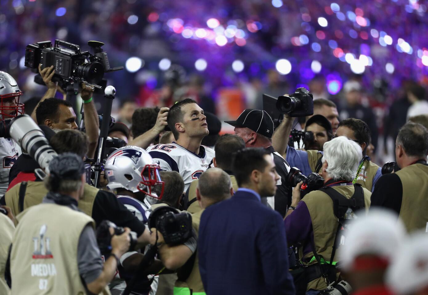 Patriots quarterback Tom Brady is surrounded by reporters and photographers after defeating the Falcons, 34-28, in overtime of Super Bowl LI.