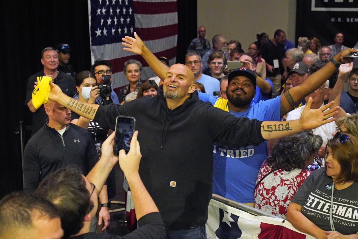 Pennsylvania Lt. Gov. John Fetterman stretched out his tattoed arms and smiles for a selfie with supporters after a rally.