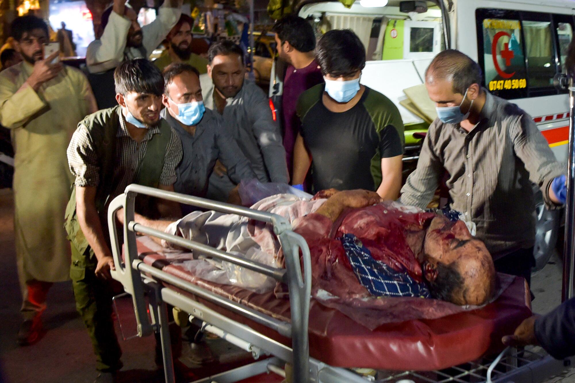 Volunteers and medical staff bring an injured man, whose body is bloodied, to the hospital for treatment.