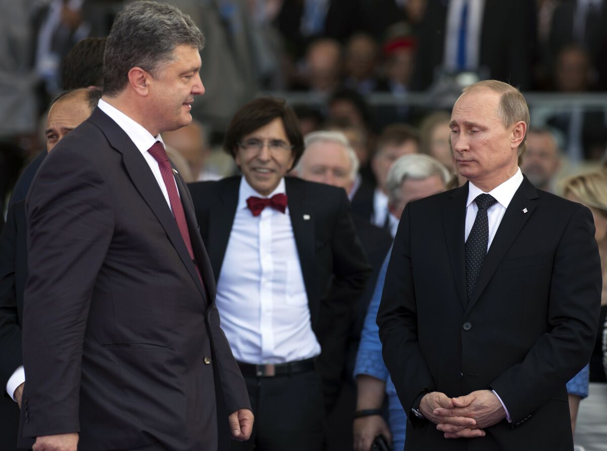 FILE - Ukrainian President Petro Poroshenko, left, walks past Russian President Vladimir Putin, right, during the commemoration of the 70th anniversary of the D-Day in Ouistreham, western France, June 6, 2014. The 2015 peace deal for eastern Ukraine was a diplomatic coup for Moscow, requiring Ukrainian authorities to offer self-rule to the Russia-backed separatist regions. (AP Photo/Alexander Zemlianichenko, file)