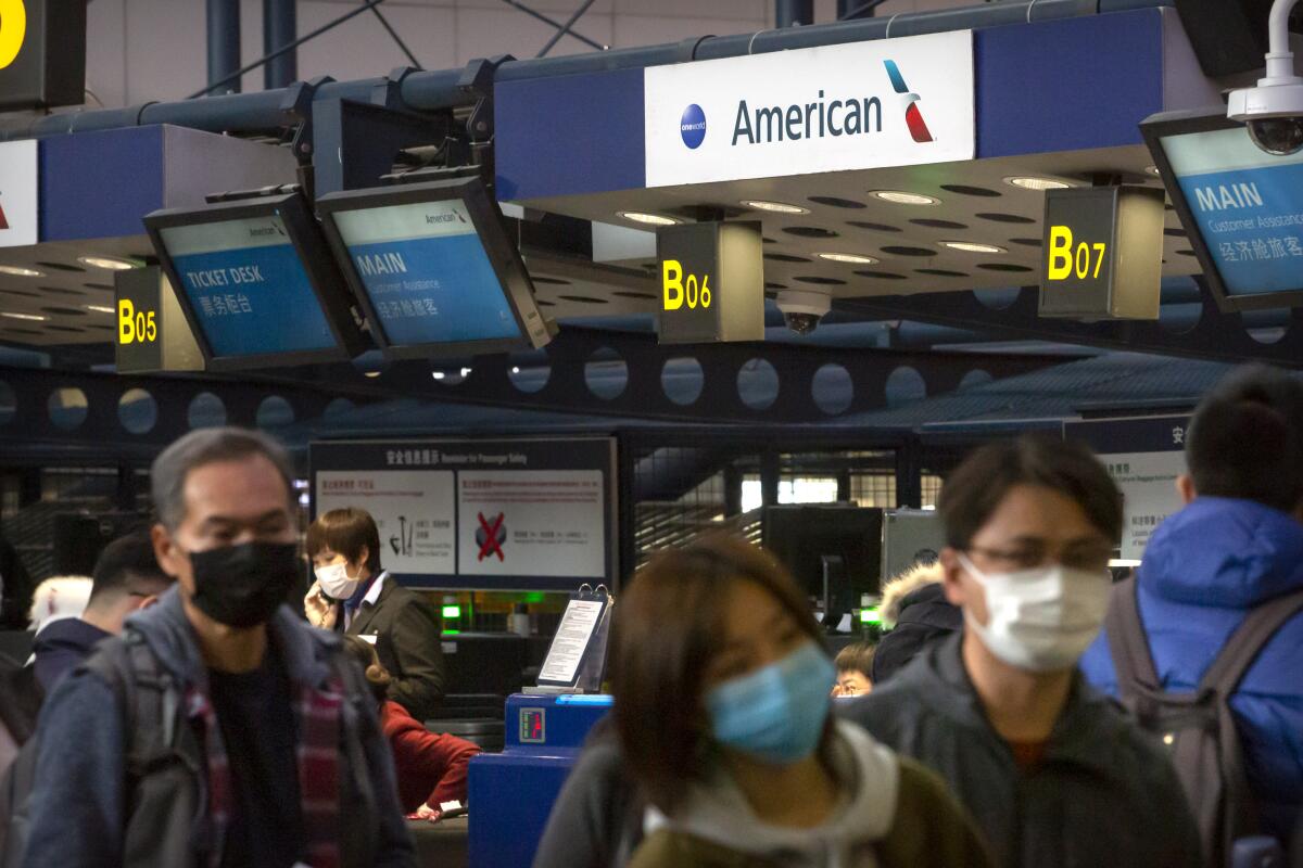 Viajeros se forman en un mostrador de American Airlines para documentar para un vuelo de Los Ángeles a Beijing.