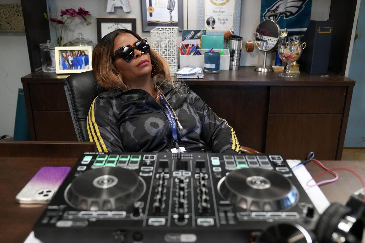 A school principal dressed as a DJ, asleep in a chair in her office