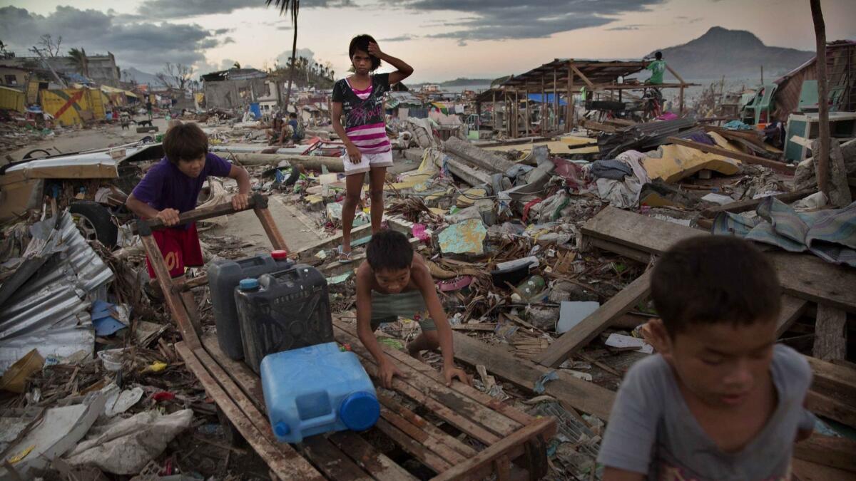Children in Tacloban, Philippines, push a cart on Nov. 18, 2013, as they collect water in an area destroyed by Typhoon Haiyan.