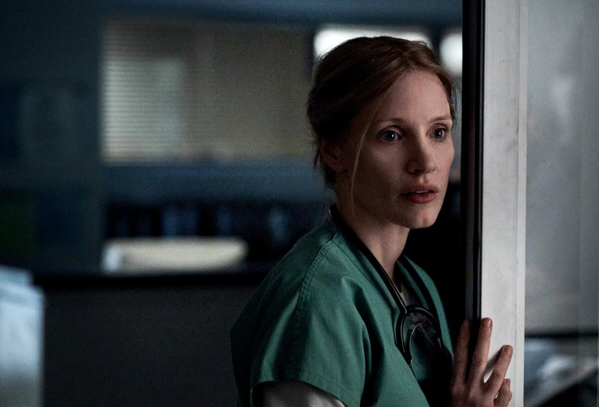Jessica Chastain stands in a doorway wearing scrubs in "The Good Nurse."