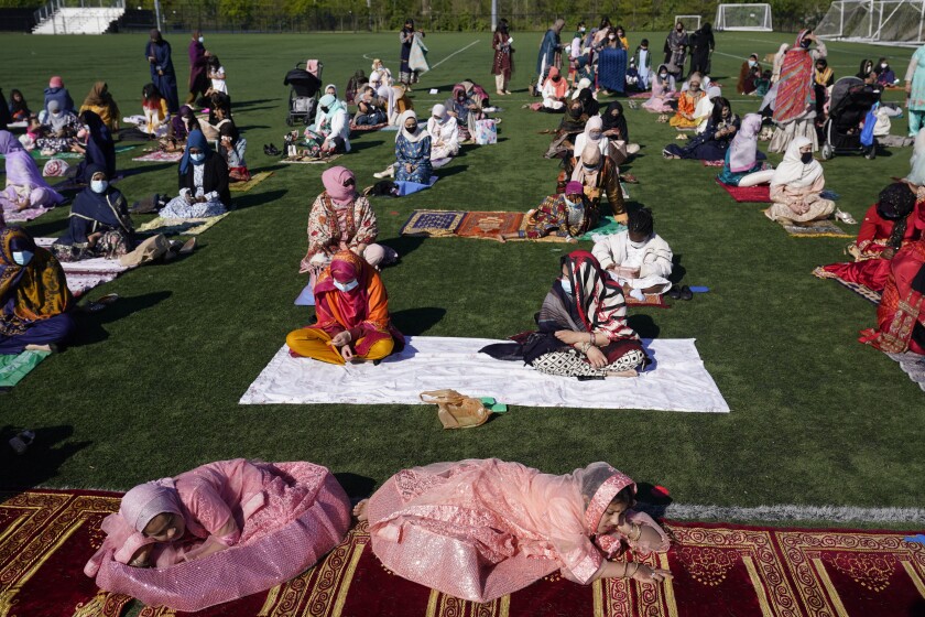 Aqsa Syeda, 8, left front, and her cousin Ameena Ahmed, 9, right front, relax before the start of Eid al-Fitr prayers in Overpeck County Park in Ridgefield Park, N.J., Thursday, May 13, 2021. Millions of Muslims across the world are marking a muted and gloomy holiday of Eid al-Fitr, the end of the fasting month of Ramadan - a usually joyous three-day celebration that has been significantly toned down as coronavirus cases soar. (AP Photo/Seth Wenig)