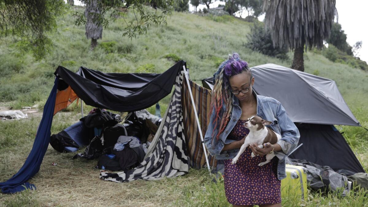 Nafeesa Ansar, who has been homeless for more than two years, stands outside her camp with her dog, Monk Monk, on Alvarado Street after a news conference to announce a campaign to shift city money from camp sweeps to homeless services.