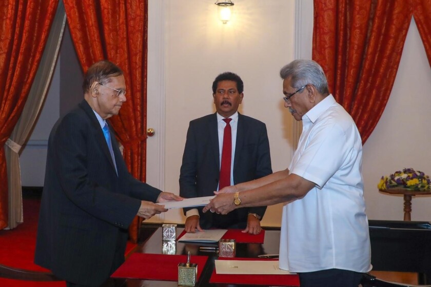 In this handout photograph provided by the Sri Lankan President's Office, President Gotabaya Rajapaksa, right, hands over the appointment document to Gamini Lakshman Peiris after he took oath of office as the new foreign minister in Colombo, Sri Lanka, Saturday, May 14, 2022. (Sri Lankan President's Office via AP)