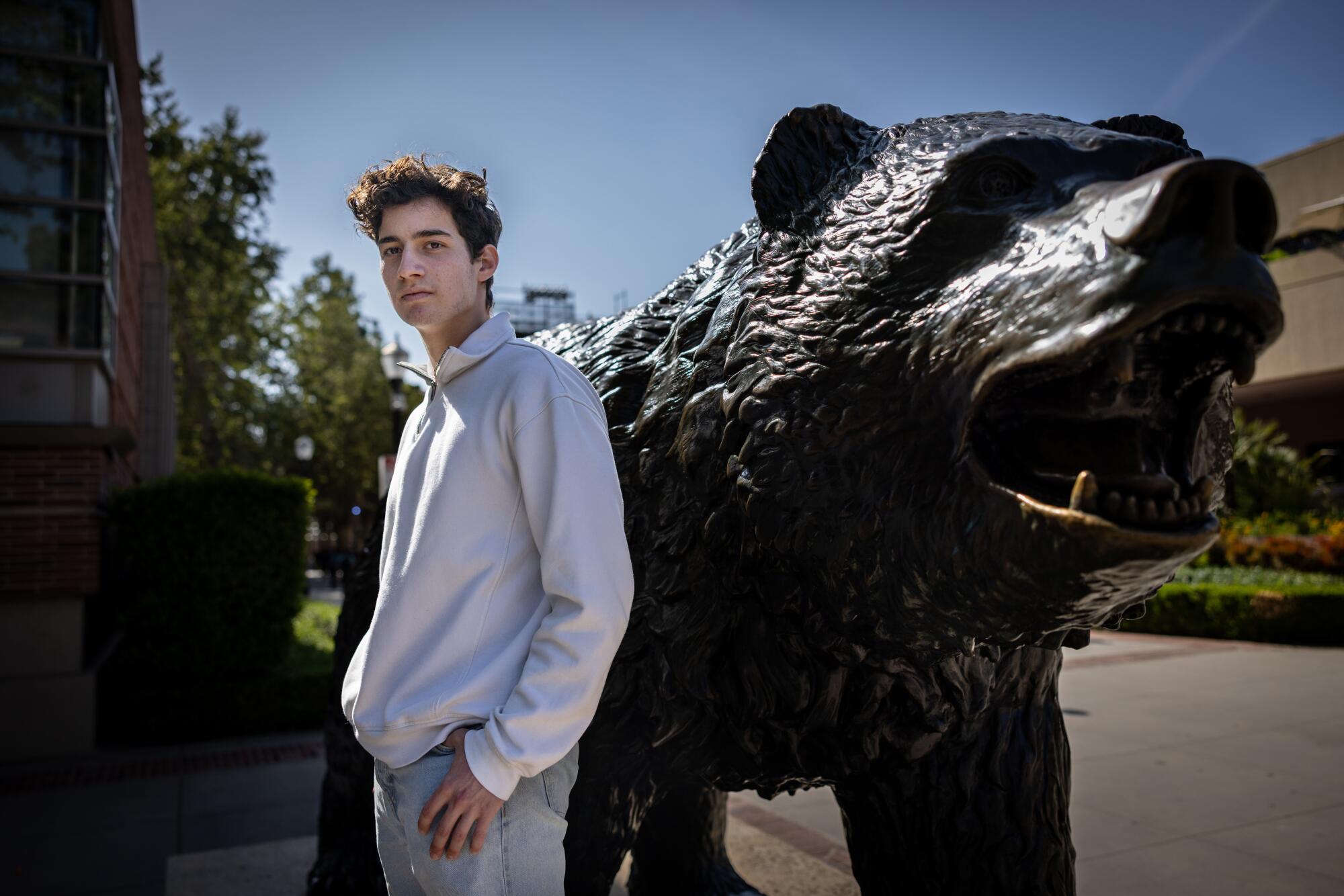 UCLA student Gal Cohavy standing beside a Bruin statue