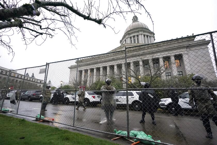 Members of the Washington National Guard stand near a fence surrounding the Capitol in anticipation of protests Monday, Jan. 11, 2021, in Olympia, Wash. State capitols across the country are under heightened security after the siege of the U.S. Capitol last week. (AP Photo/Ted S. Warren)