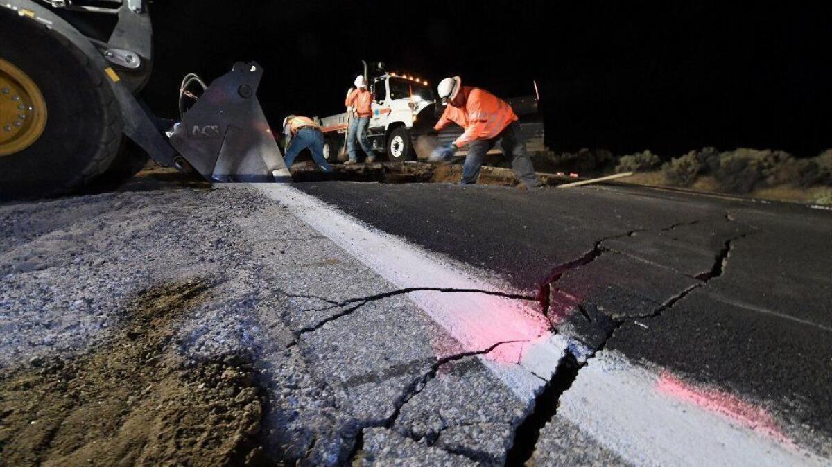 Highway workers repair part of a road damaged by the magnitude 7.1 earthquake on July 5 near Ridgecrest, Calif.