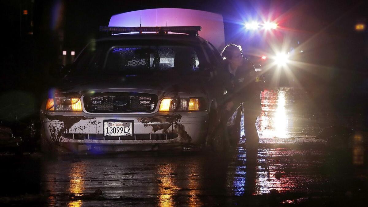 A sheriff's deputy works to free a patrol car from mud on a stretch of Pacific Coast Highway in Malibu on Saturday night.