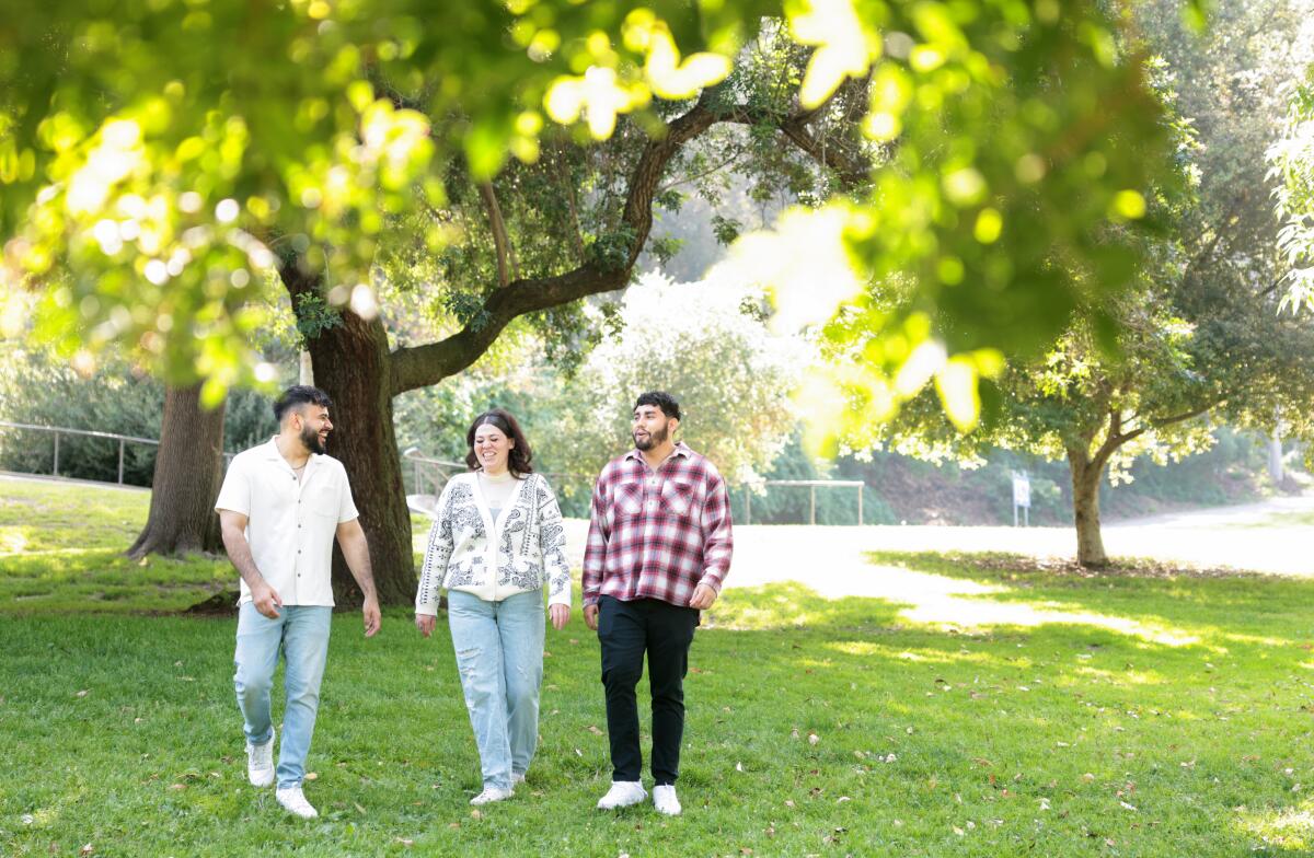 Three people walking through a park.