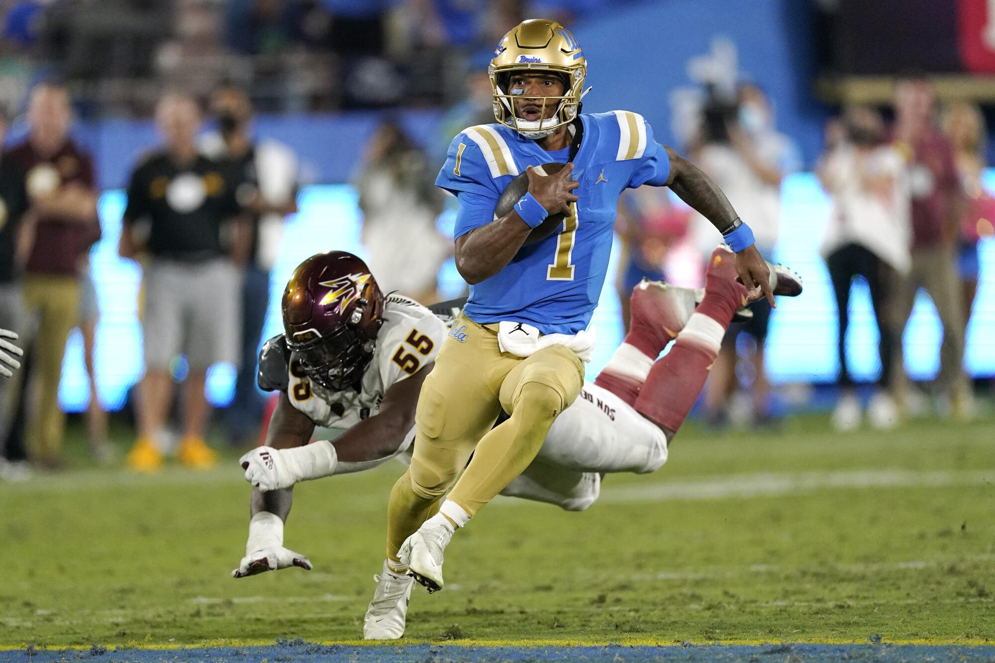 CLA quarterback Dorian Thompson-Robinson, right, avoids a tackle by Arizona State defensive lineman Omarr Norman-Lott.