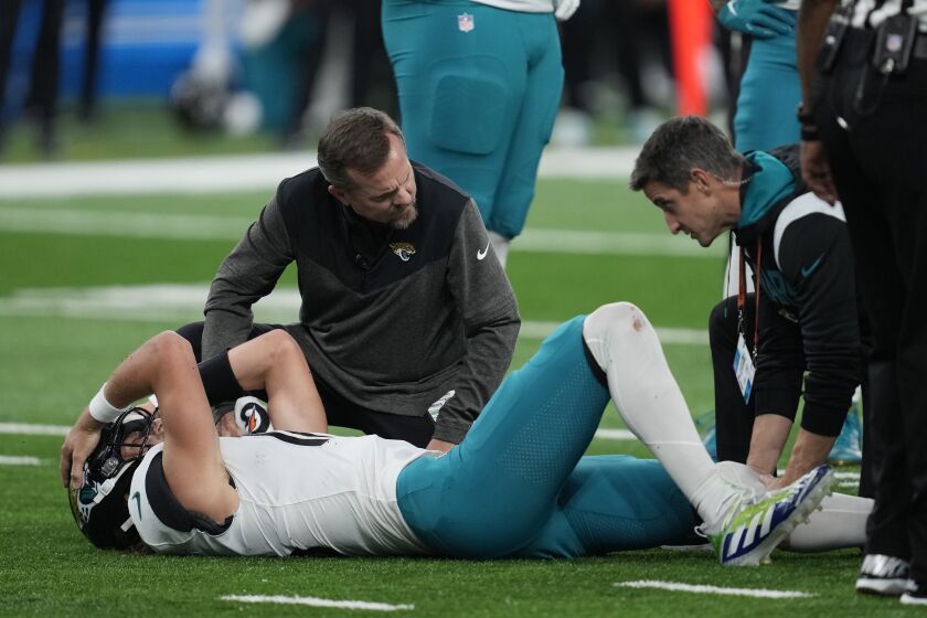 Jacksonville Jaguars quarterback Trevor Lawrence is examined after a sack during the first half of an NFL football game against the Detroit Lions, Sunday, Dec. 4, 2022, in Detroit. (AP Photo/Paul Sancya)