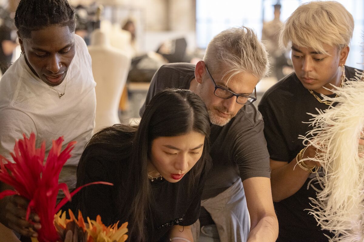 Four contestants look at a design in "Project Runway" on Bravo.
