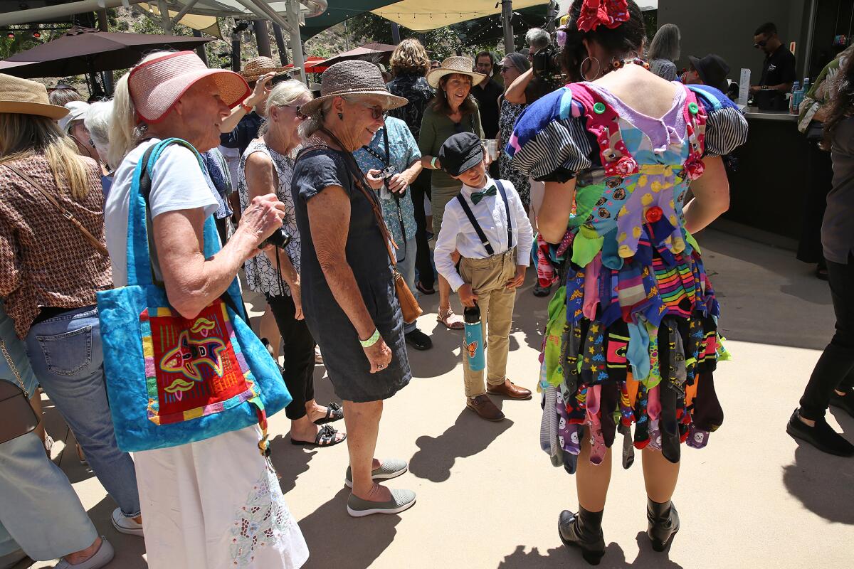 Guests surround artist Elizabeth McGhee for a closer look at her dress creation at the Festival of Arts runway fashion show.