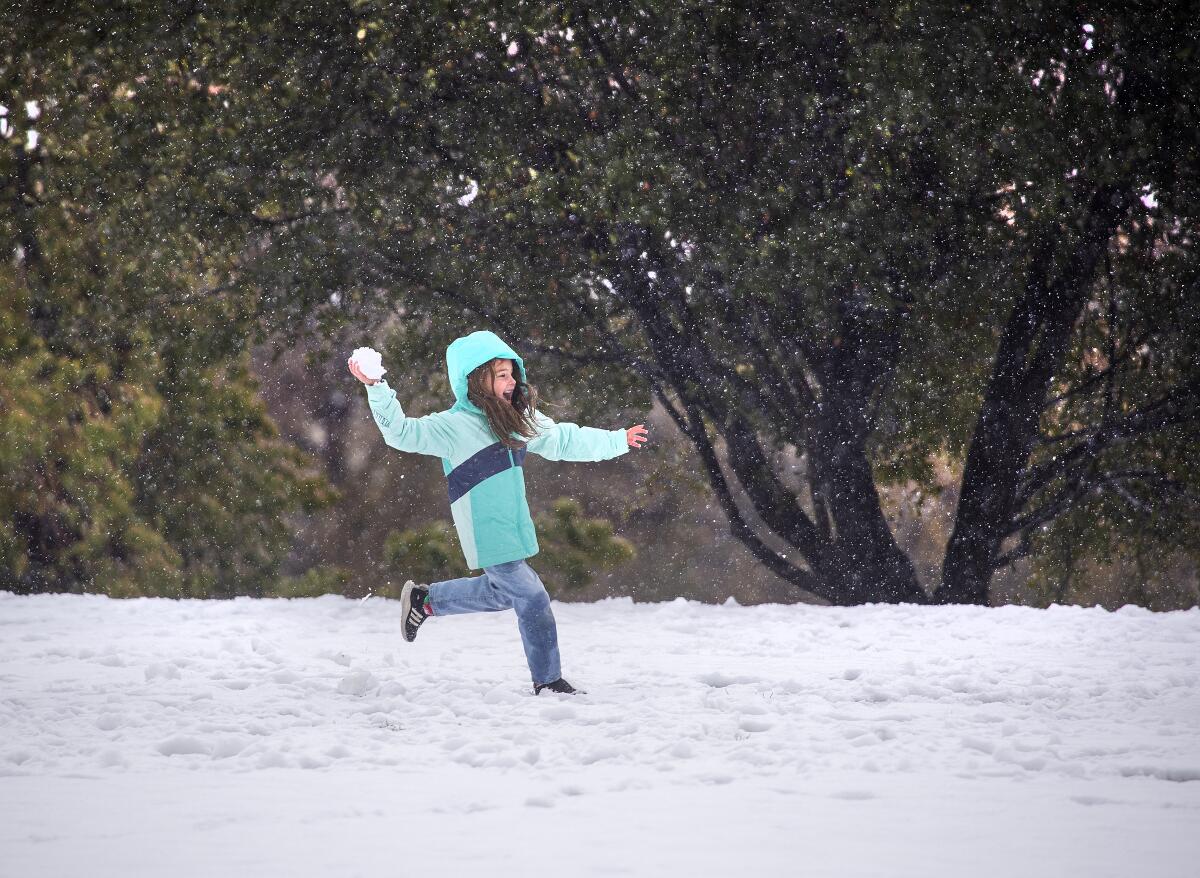 A child runs through the falling snow during a snowball fight 