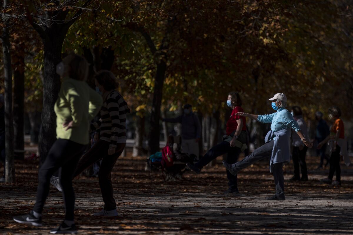 People wearing a face masks to prevent the spread of coronavirus make exercise at the Retiro park in Madrid, Spain, Thursday, Nov. 11, 2020. Spain's health ministry is reporting 411 more fatalities for the coronavirus on Tuesday, a new daily record since contagion started picking up pace this summer. (AP Photo/Manu Fernandez)
