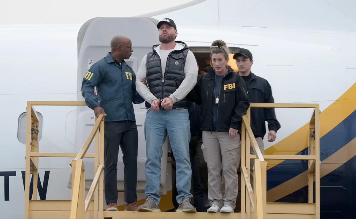A man is led off a plane by FBI agents