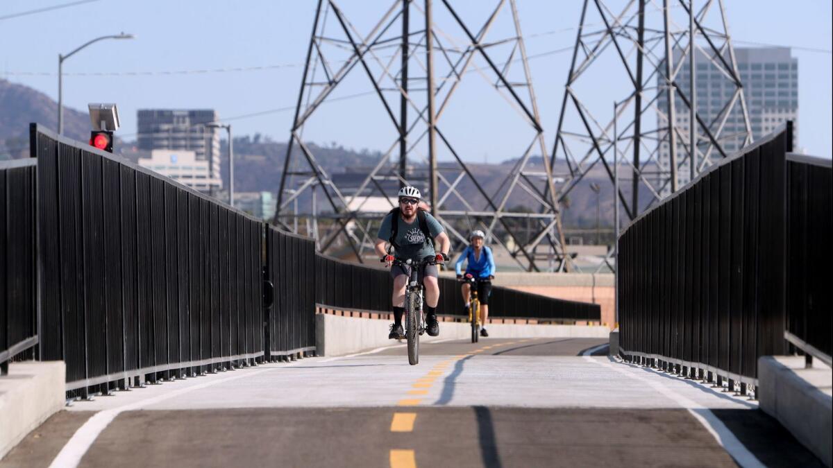 Cyclists pass over a newly constructed pedestrian and bicycle bridge over a culvert near Flower Street and Fairmont Avenue on a recent Saturday. The bridge is part of the second phase of the Glendale Narrows Riverwalk project.