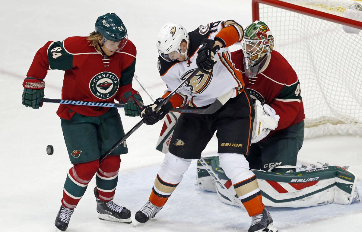 Ducks’ Corey Perry, center, has problems getting to the puck as Minnesota’s Mikael Granlund, left, helps goalie Devan Dubnyk defend the net on Saturday.