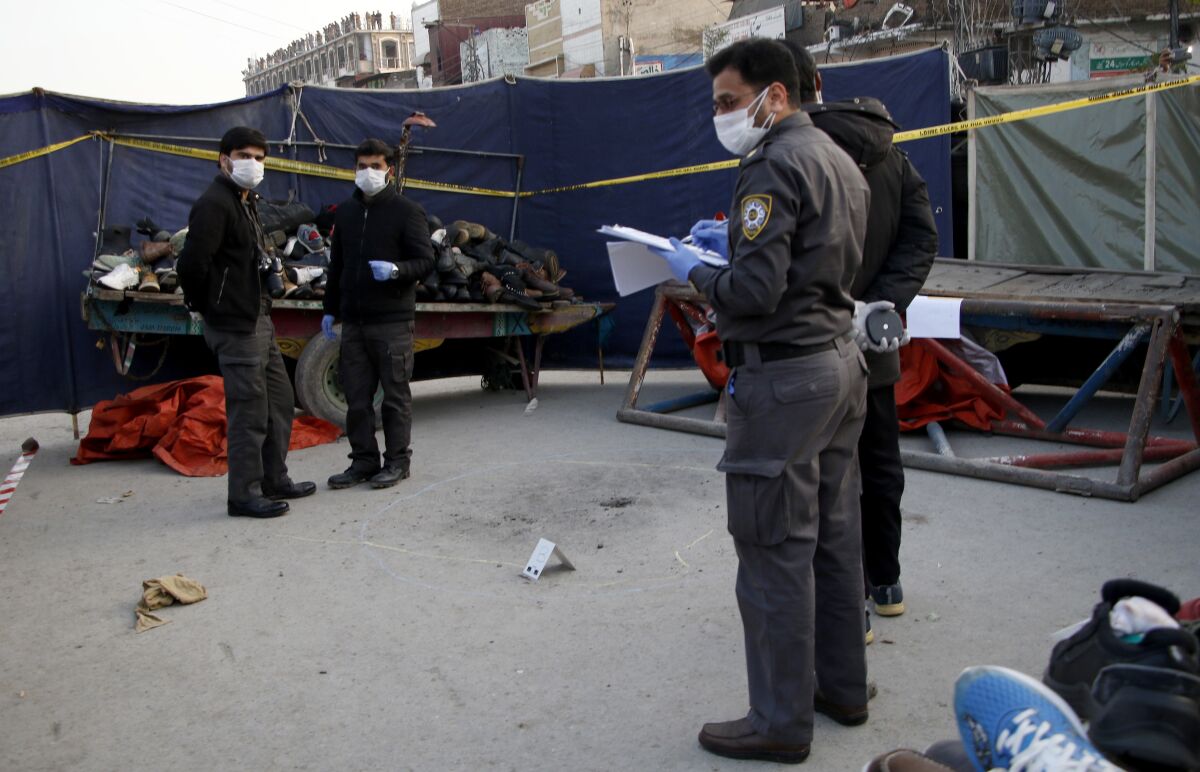 Pakistani investigators examine the site of a bomb explosion, in Rawalpindi, Pakistan, Sunday, Dec. 13, 2020. The roadside bomb exploded near a police station in the Pakistani garrison city of Rawalpindi on Sunday, wounding many people, police said. (AP Photo/A.H. Chaudary)